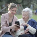 Jonge vrouw helpt oudere vrouw met mobiele telefoon